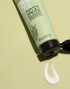 An open tube of KMS consciousstyle beach style creme with some product applied to a smooth surface